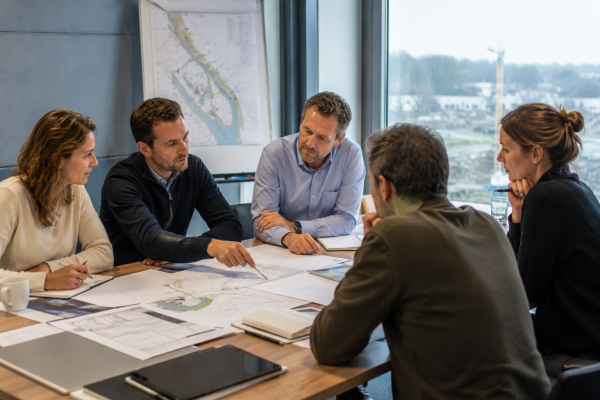 Professionals van opdrachtgever en opdrachtnemer werken samen aan technische tekeningen voor een infraproject